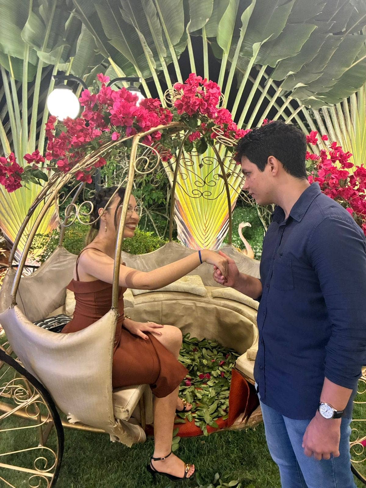 O casal de mãos dadas em um balanço decorado com flores