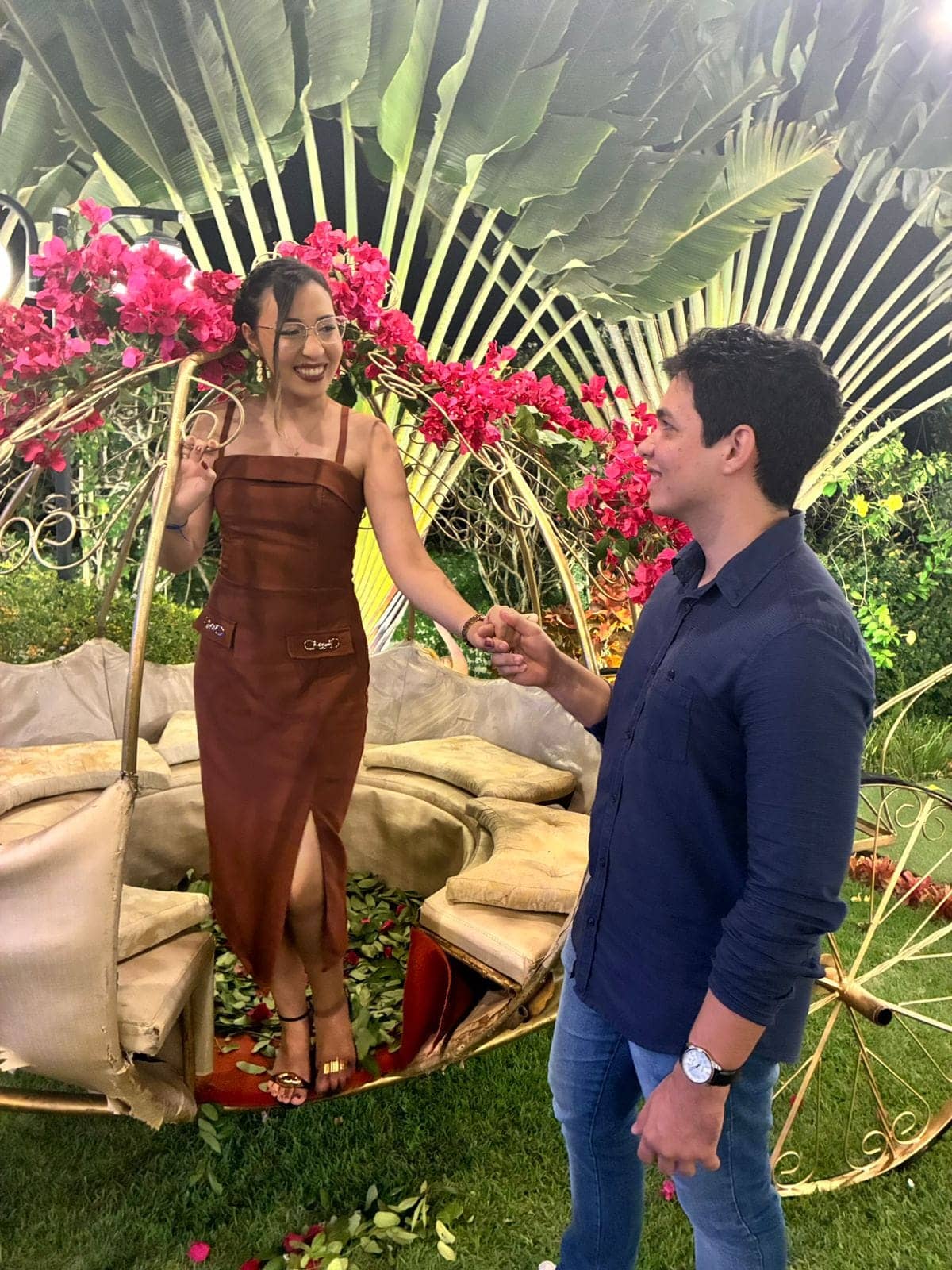 Kellyane em vestido elegante e Jonas de mãos dadas em um jardim florido