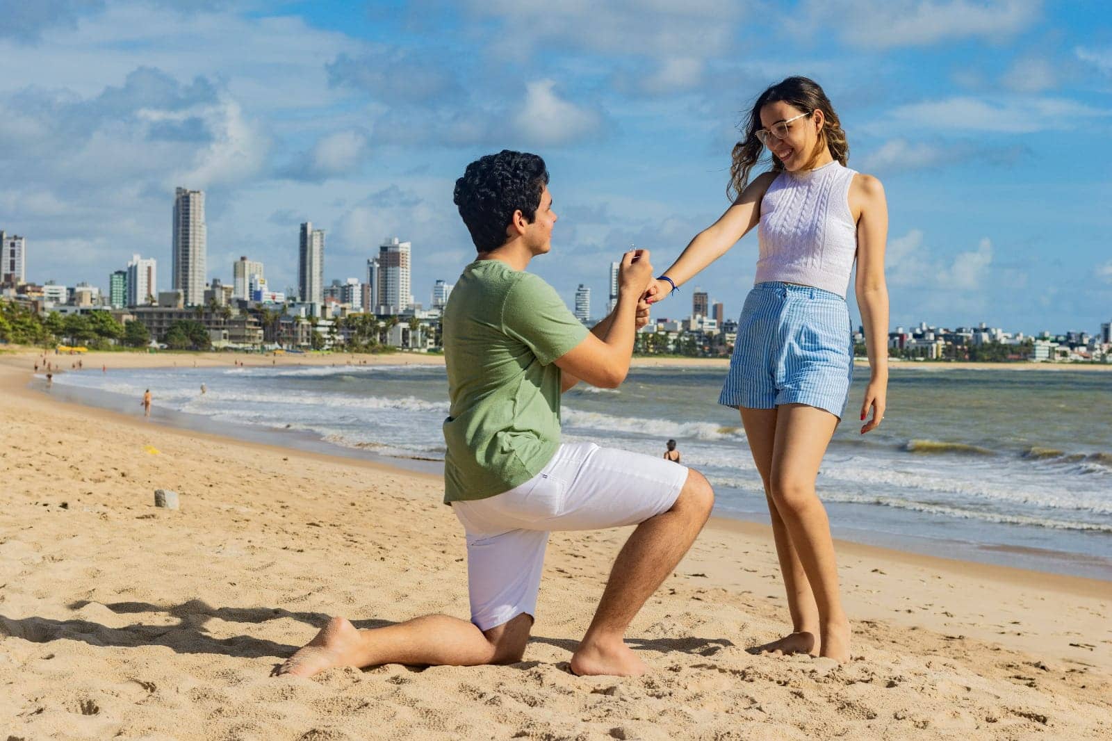 Jonas ajoelhado na areia segurando a mão de Kellyane