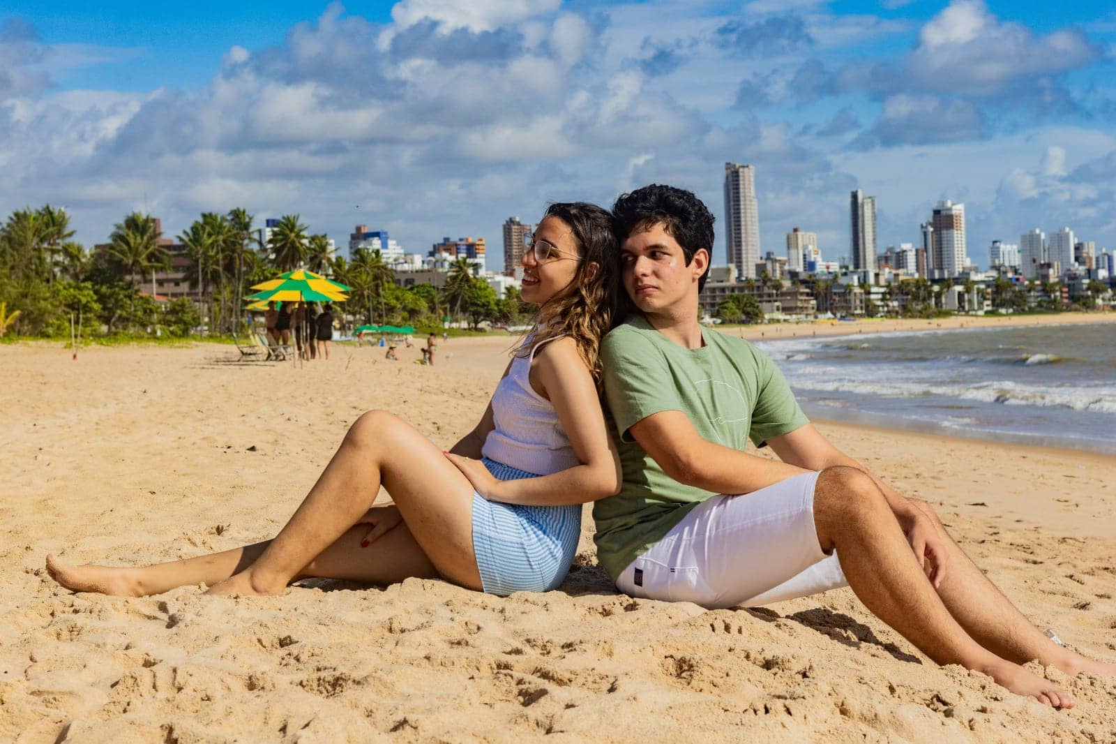 Jonas e Kellyane sentados de costas um para o outro na areia